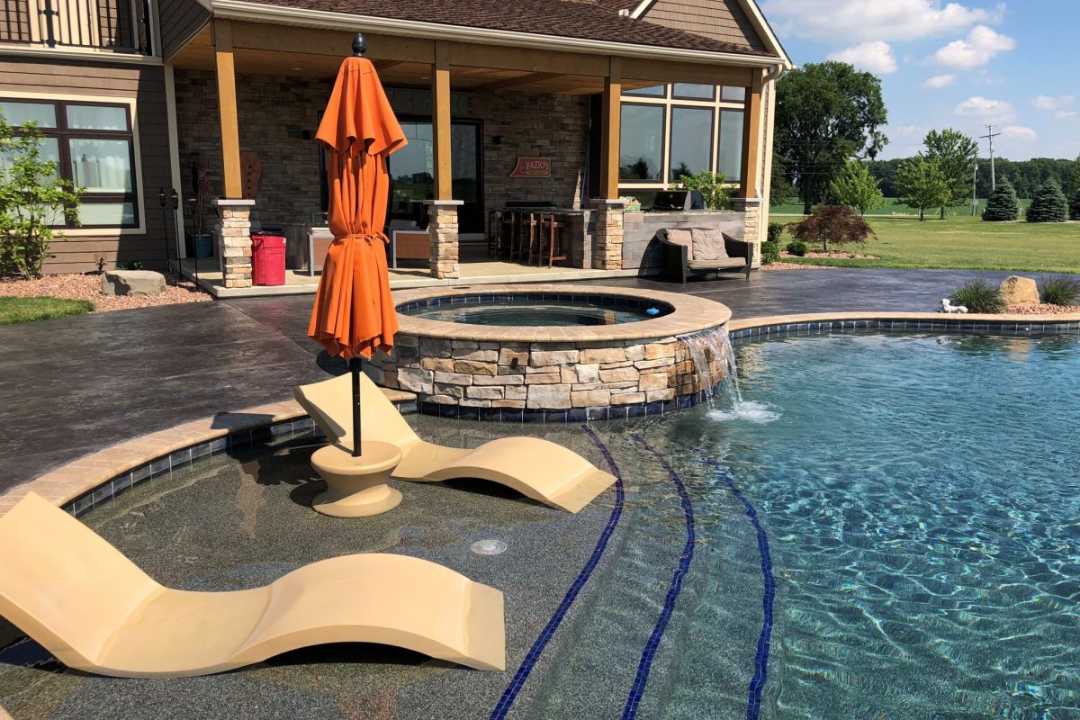 A shotcrete pool with glass trim tile and a hot tub